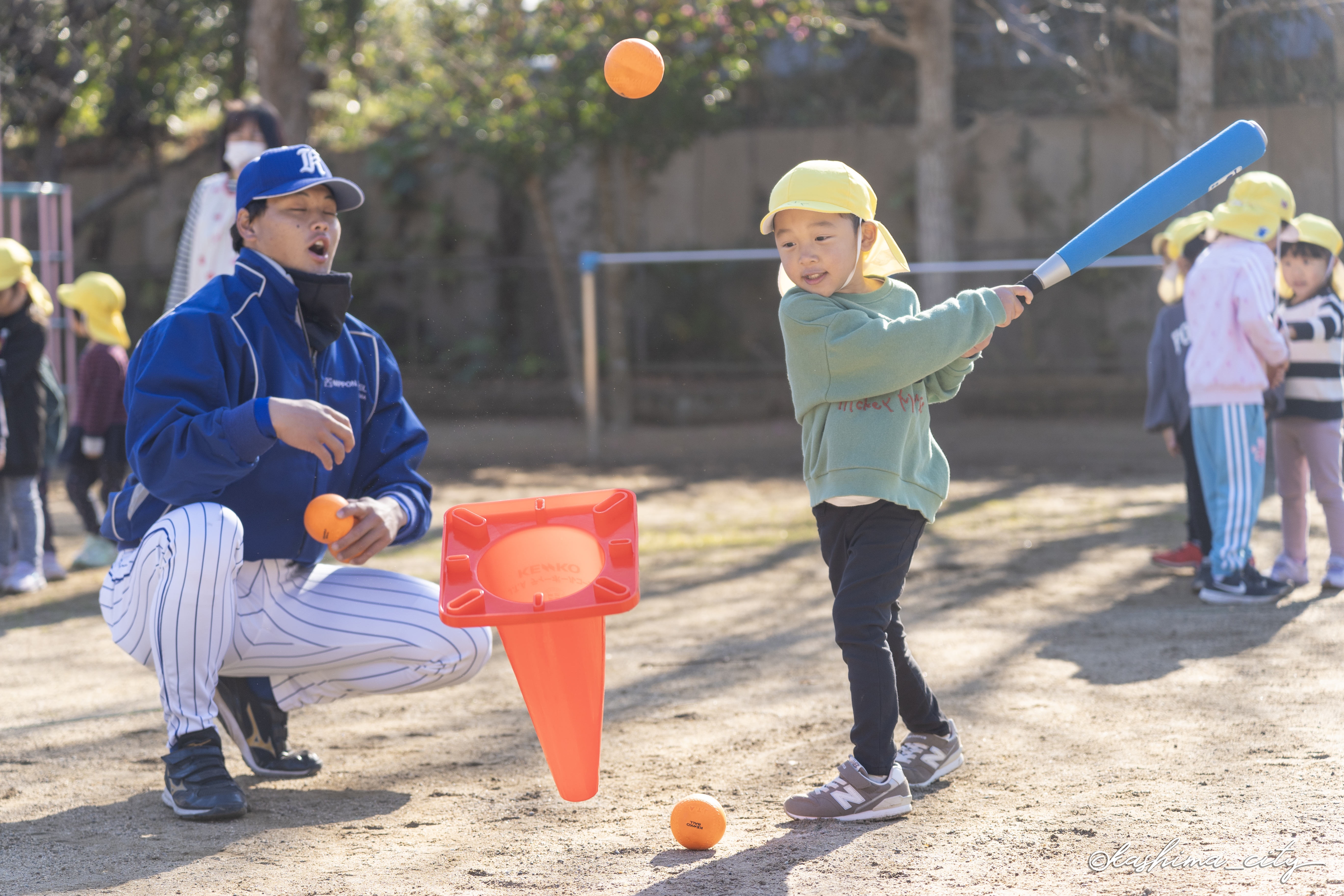 ティーバッティングする男の子と驚く選手