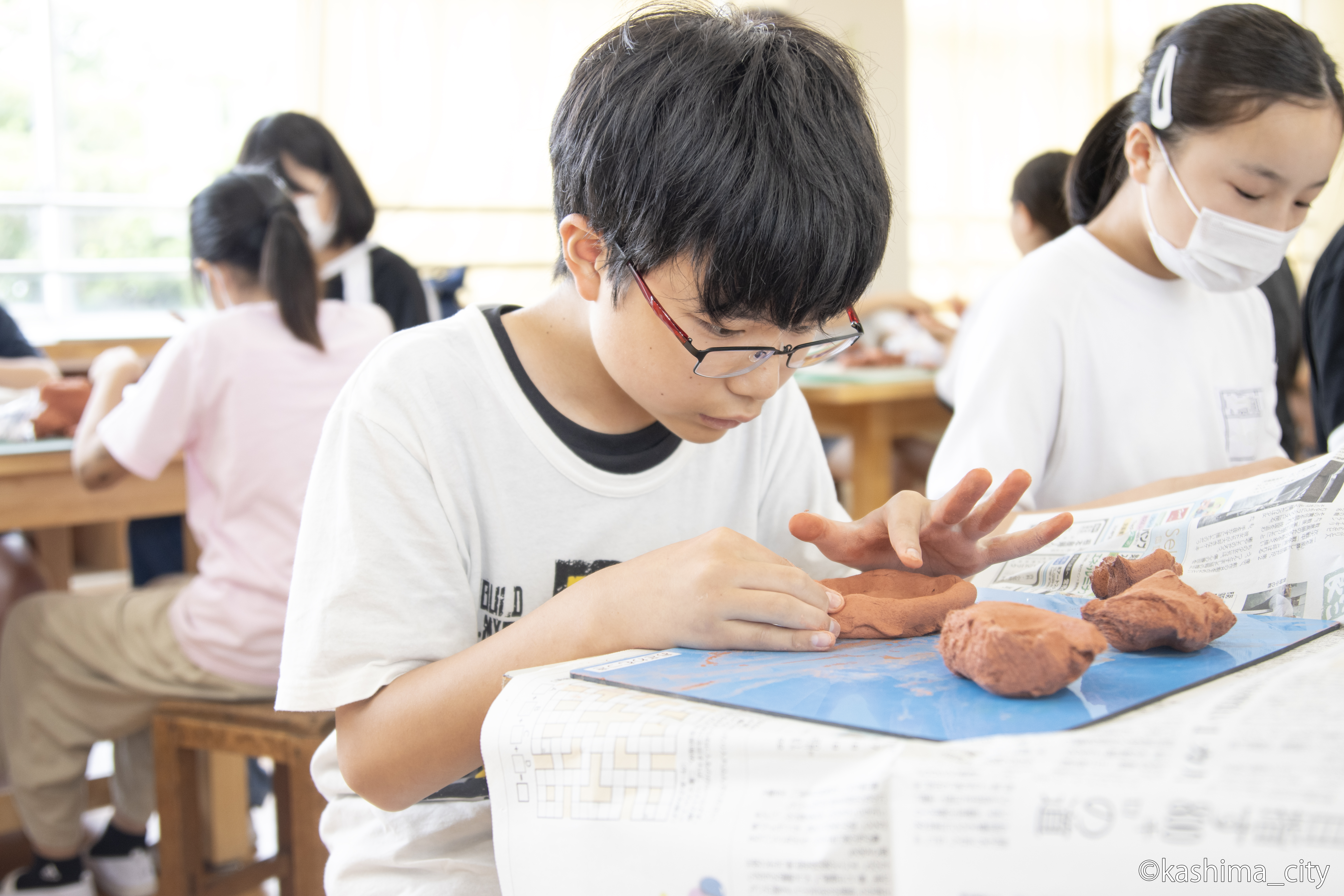 男子児童が土器の底を作る様子