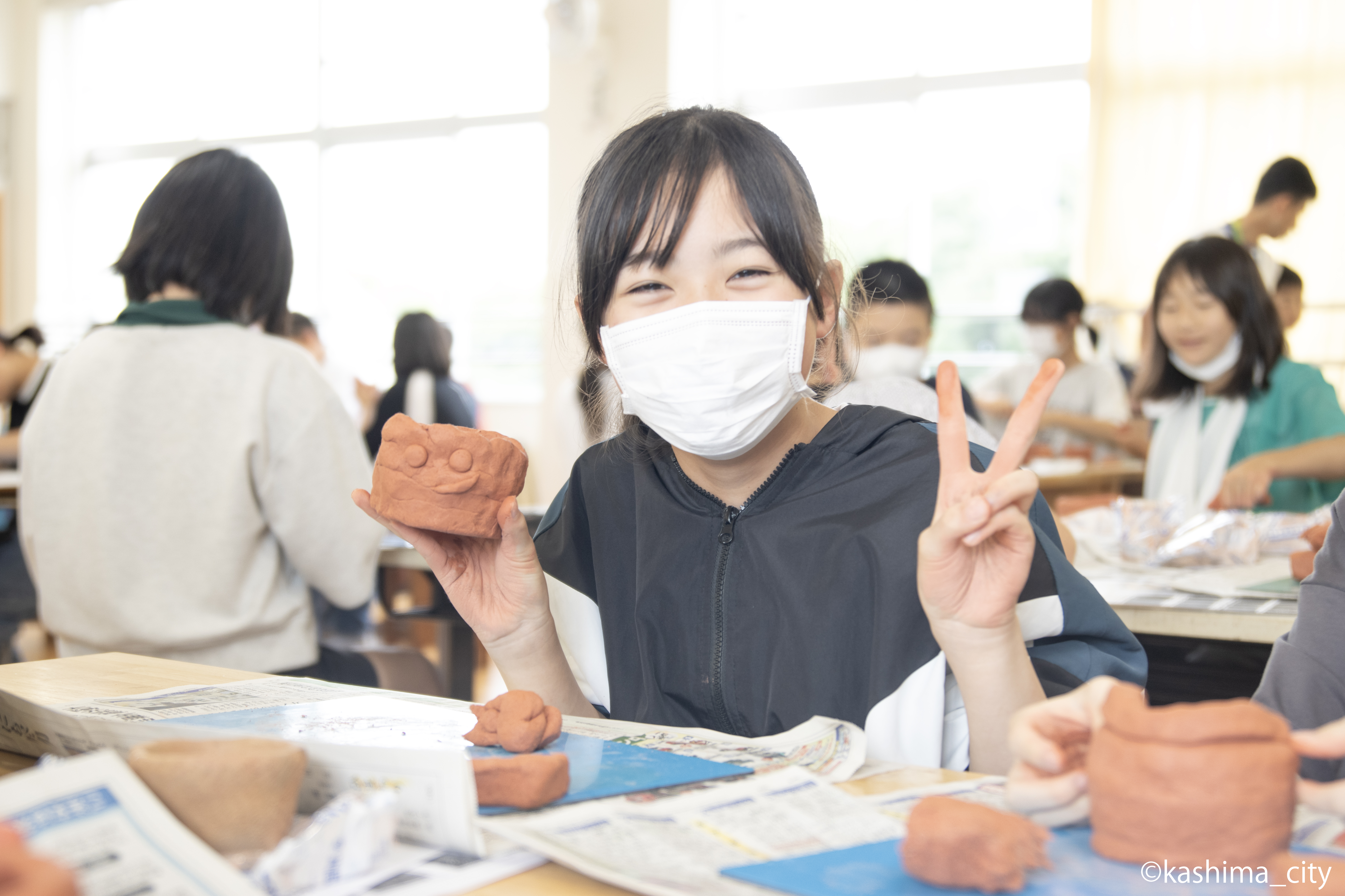 笑顔の女子児童が製作途中の土器を見せてくれる様子