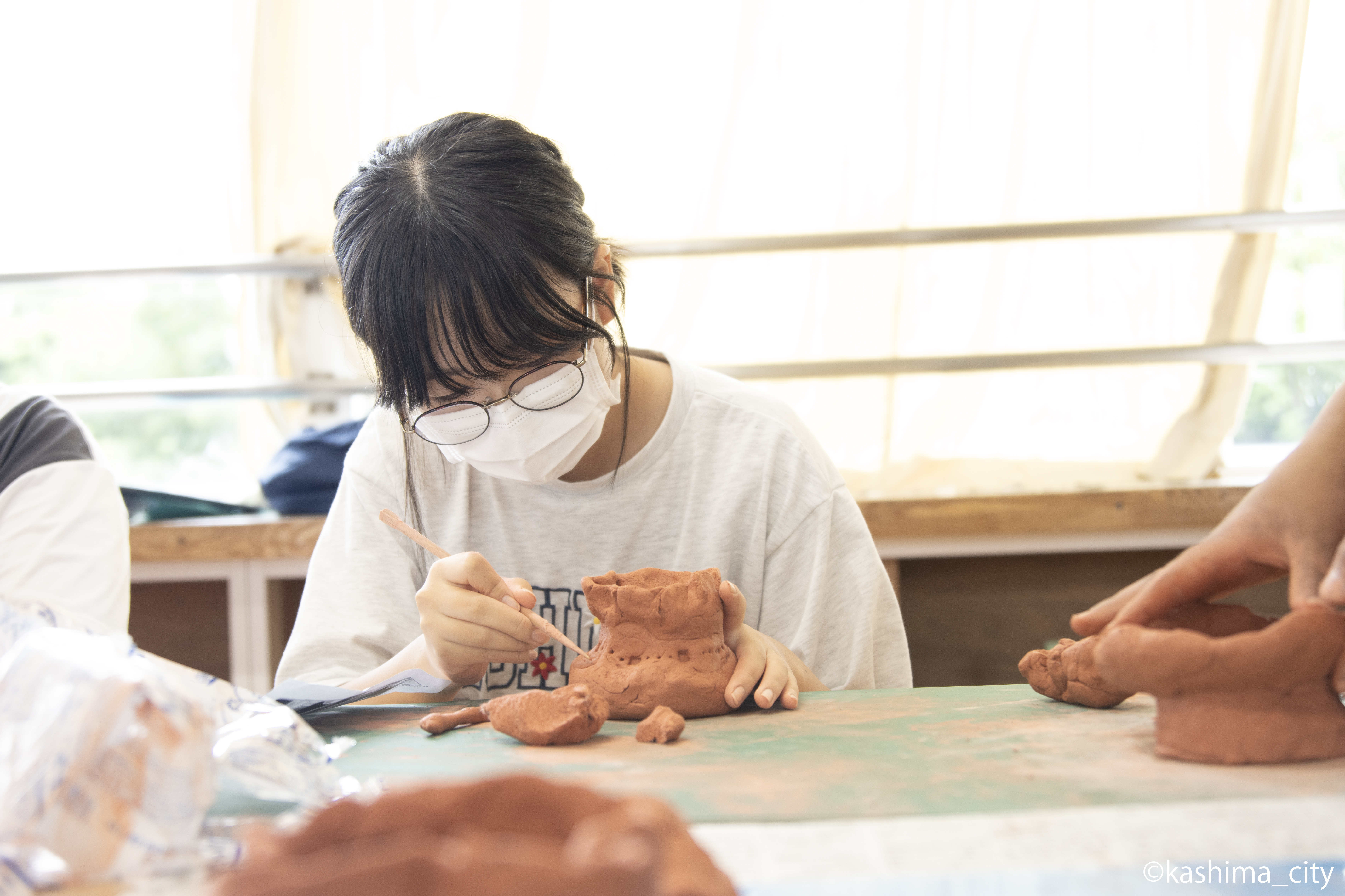 女子児童が木の棒で土器に模様を描く様子