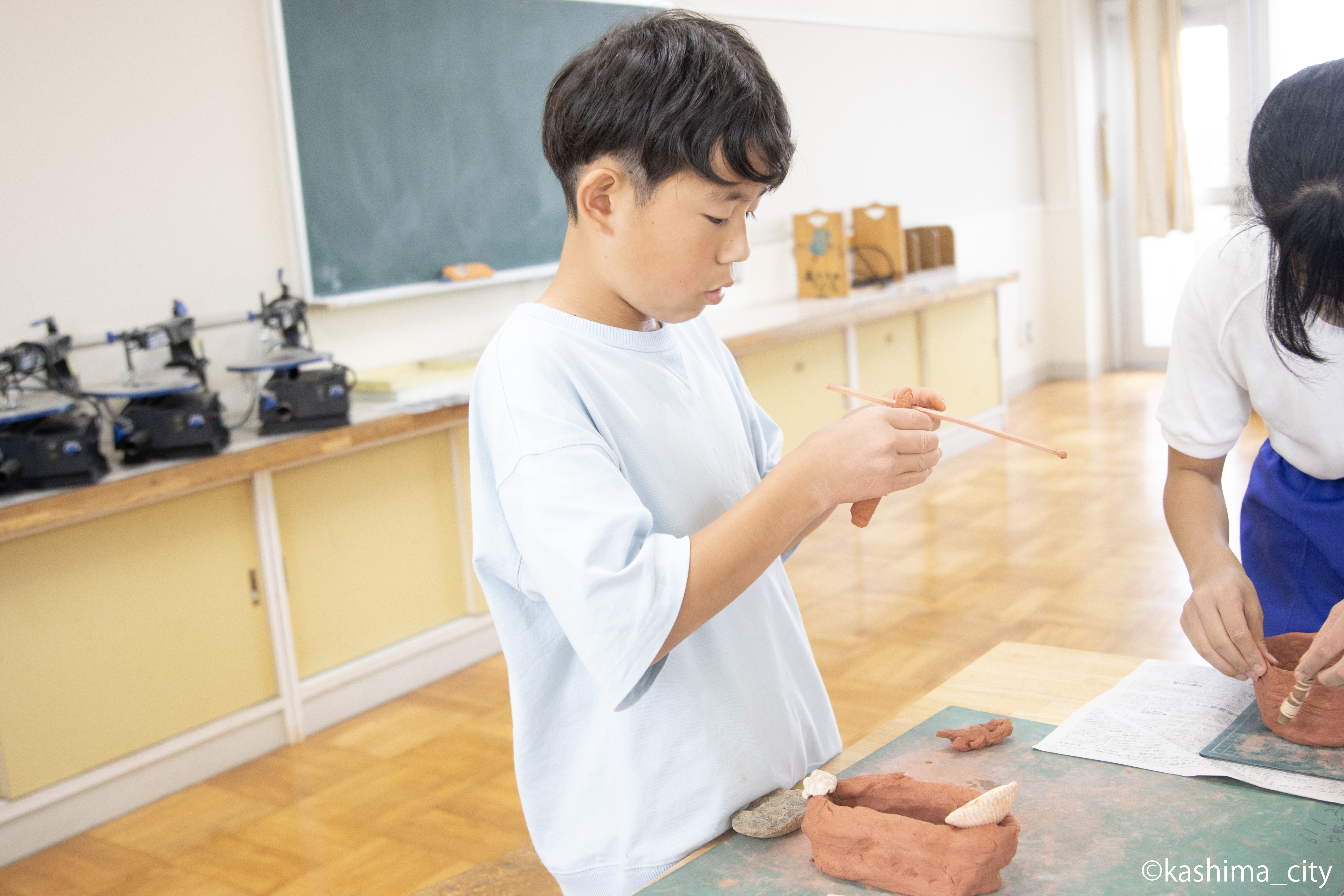 男子児童が粘土を細長く加工する様子