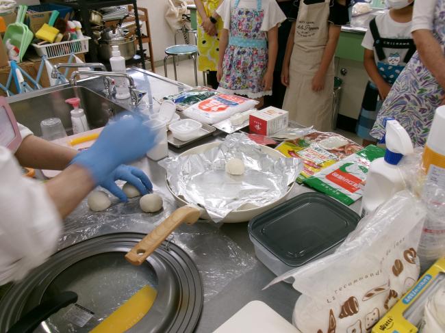 パン生地をフライパンにおく先生