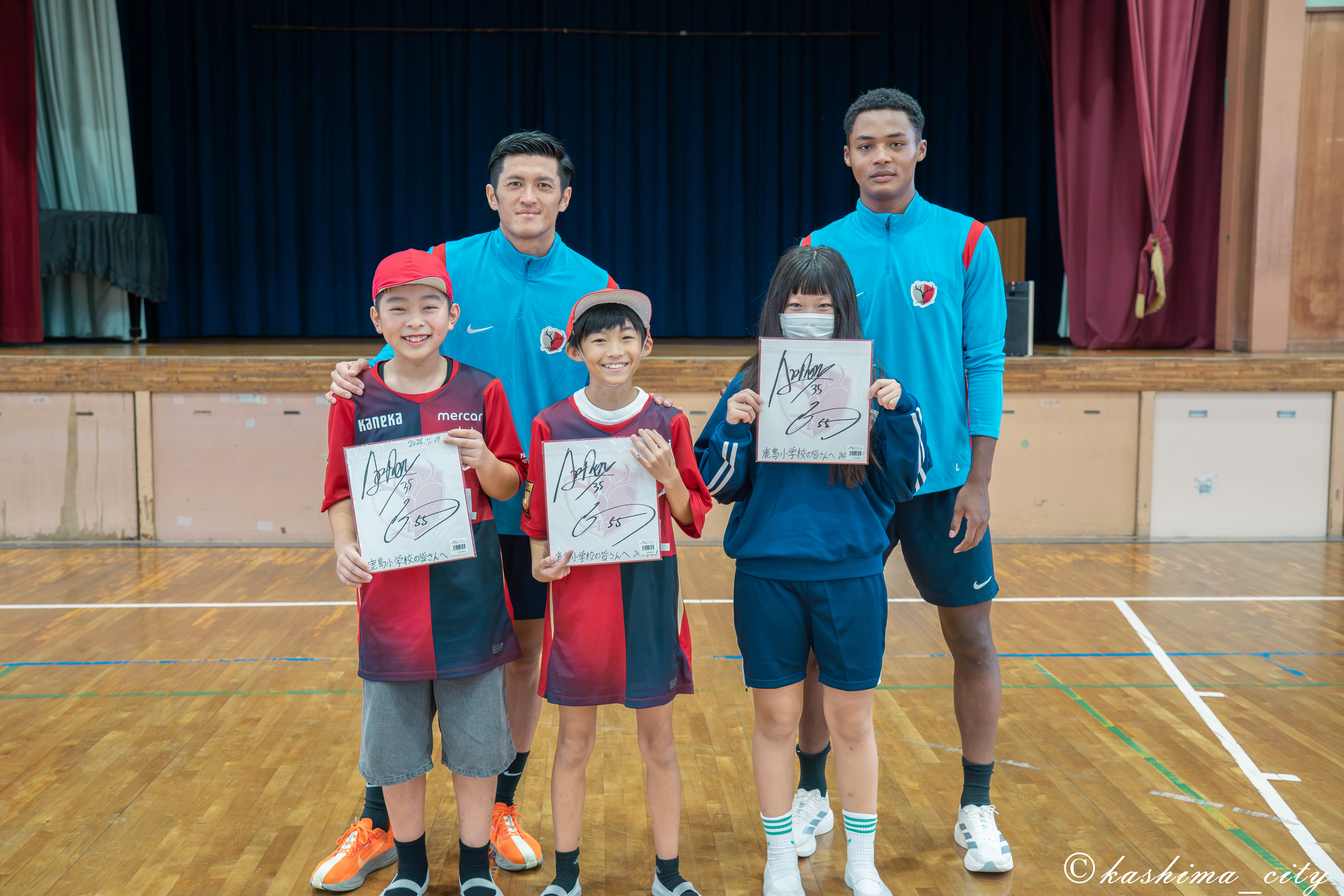 植田選手、ウデンバ選手からサイン色紙を贈呈された児童たち
