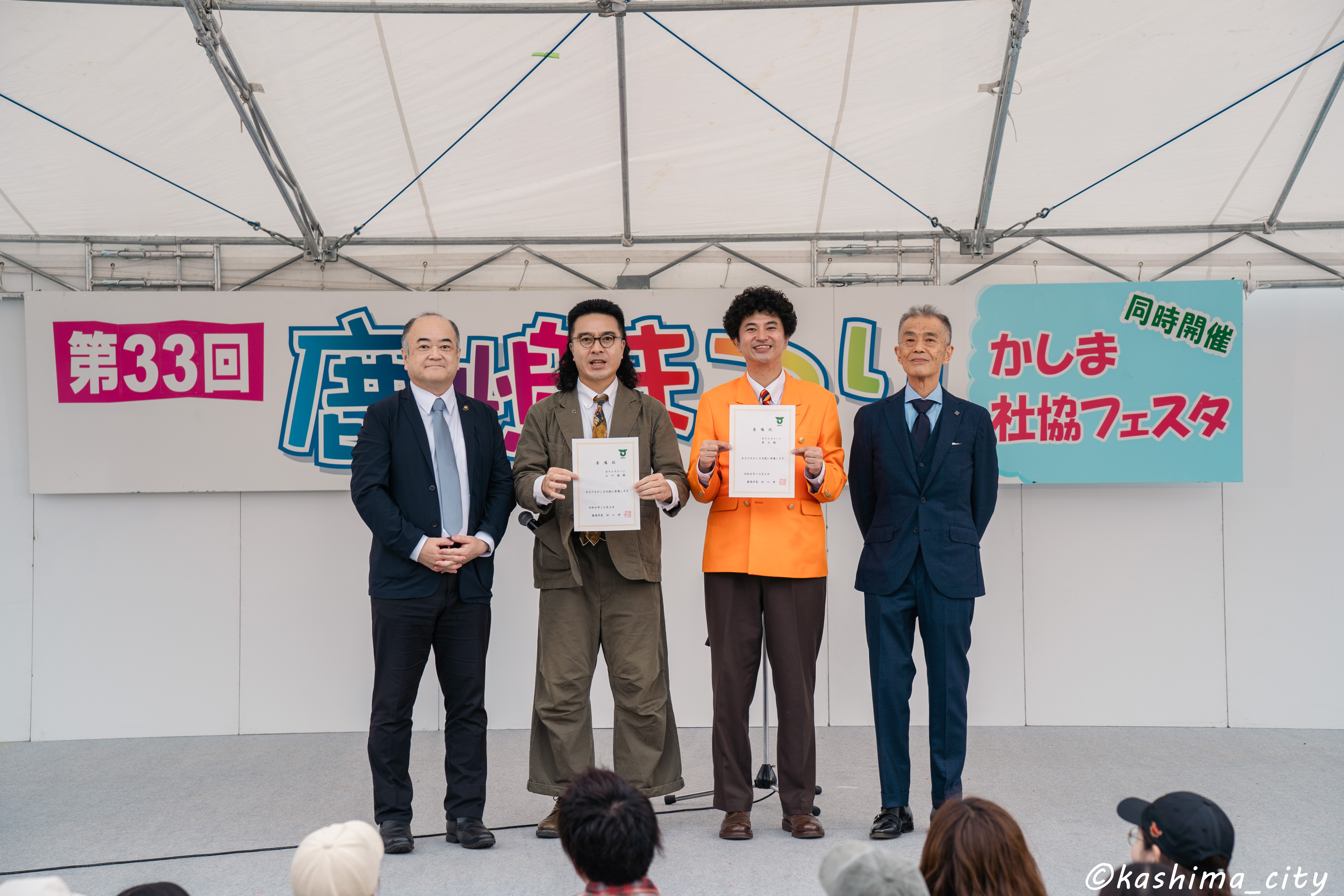 委嘱状を手にするカナメストーンと鹿嶋市長、副市長